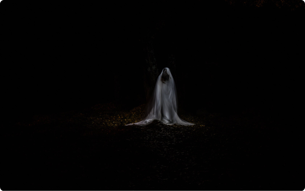 A ghostly figure draped in white stands alone in the darkness, her veil trailing to the ground—La Llorona, forever mourning the boys she lost.