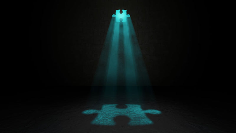 A glowing puzzle piece in a dark room, illuminated by a beam of teal light shining from above. Its shadow on the ground suggests it is the missing piece to a much larger puzzle. This image represents the identification of 'Candle Face Victims 40 and 41' f