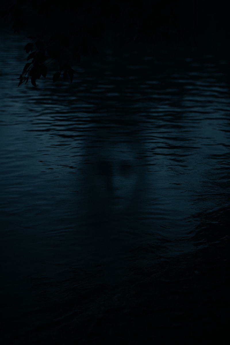 A dark, moody view of Lady Bird Lake at night. The water’s surface is still, with faint ripples. Reflected in the water is a barely visible, ghostly face or shadow, its features soft and indistinct, evoking the eerie presence of Isabel.