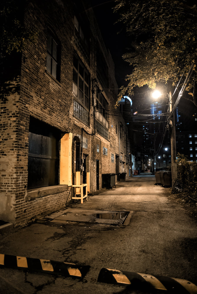 A dimly lit alleyway at night, lined with old brick buildings and scattered debris—capturing the atmosphere in the journal entry 'Limping Through the Night of Austin.' – Candle Face Chronicles.