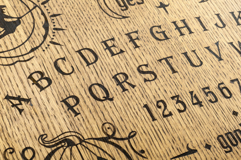 A close-up of a wooden spirit board with bold black letters, numbers, and mystical symbols engraved on its surface. Image titled 'Unveiling Lost Souls: A Breakthrough in Spirit Communication.'