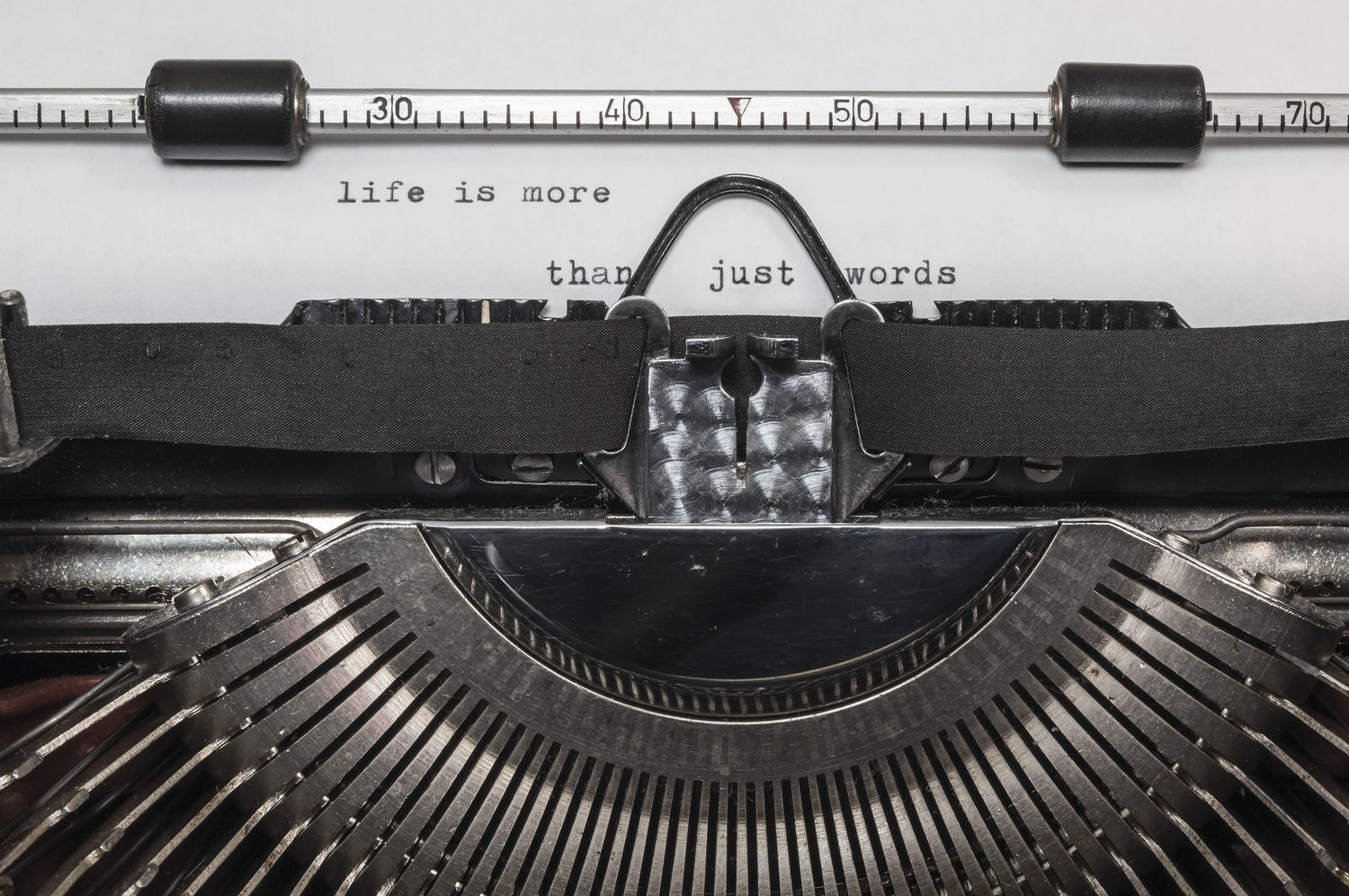 Close-up of a vintage typewriter with "life is more than just words" typed on the page.