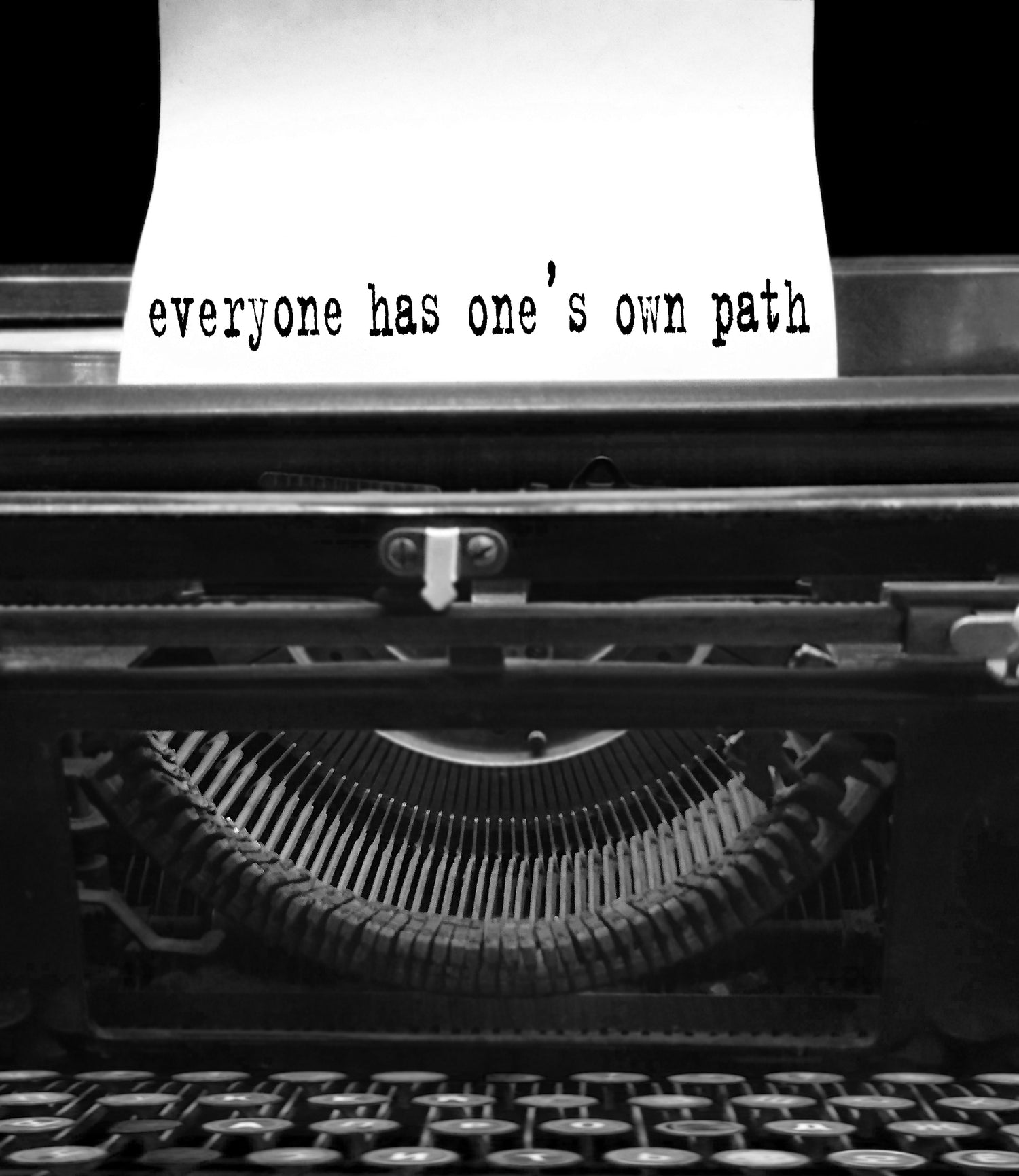 Vintage typewriter in black and white with "everyone has one's own path" typed on the page.