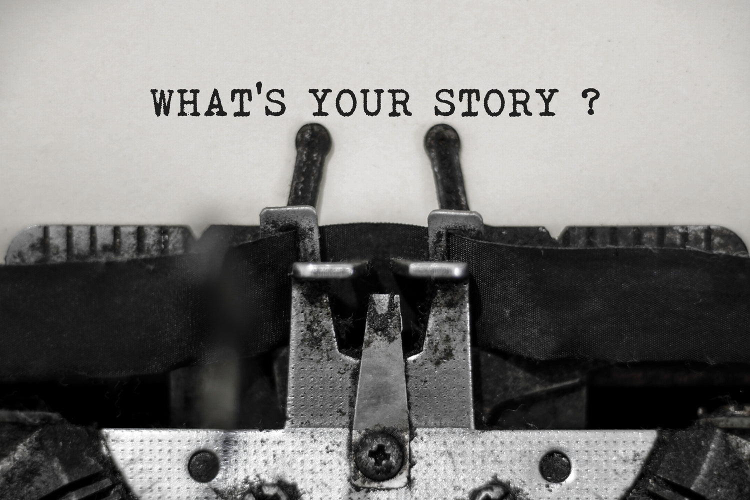 Typewriter with 'What's Your Story?' text on a plain background