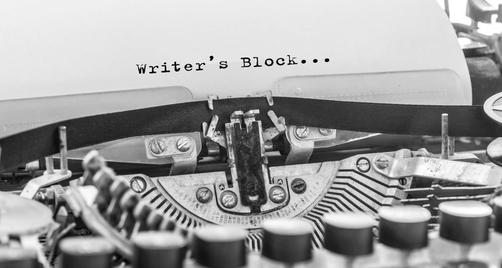 Close-up of a typewriter with 'Writer's Block' text on a white background
