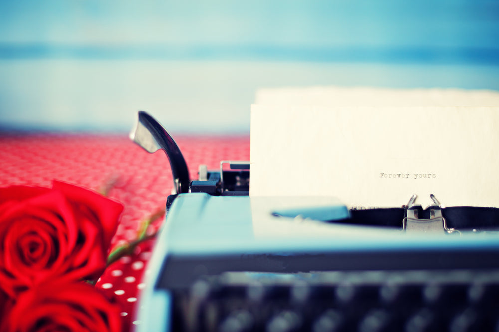 Vintage typewriter with a red rose on a blurred background